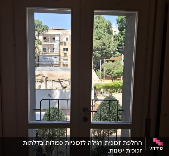 דלת זכוכית עם נוף חיצוני של בניינים ועצים